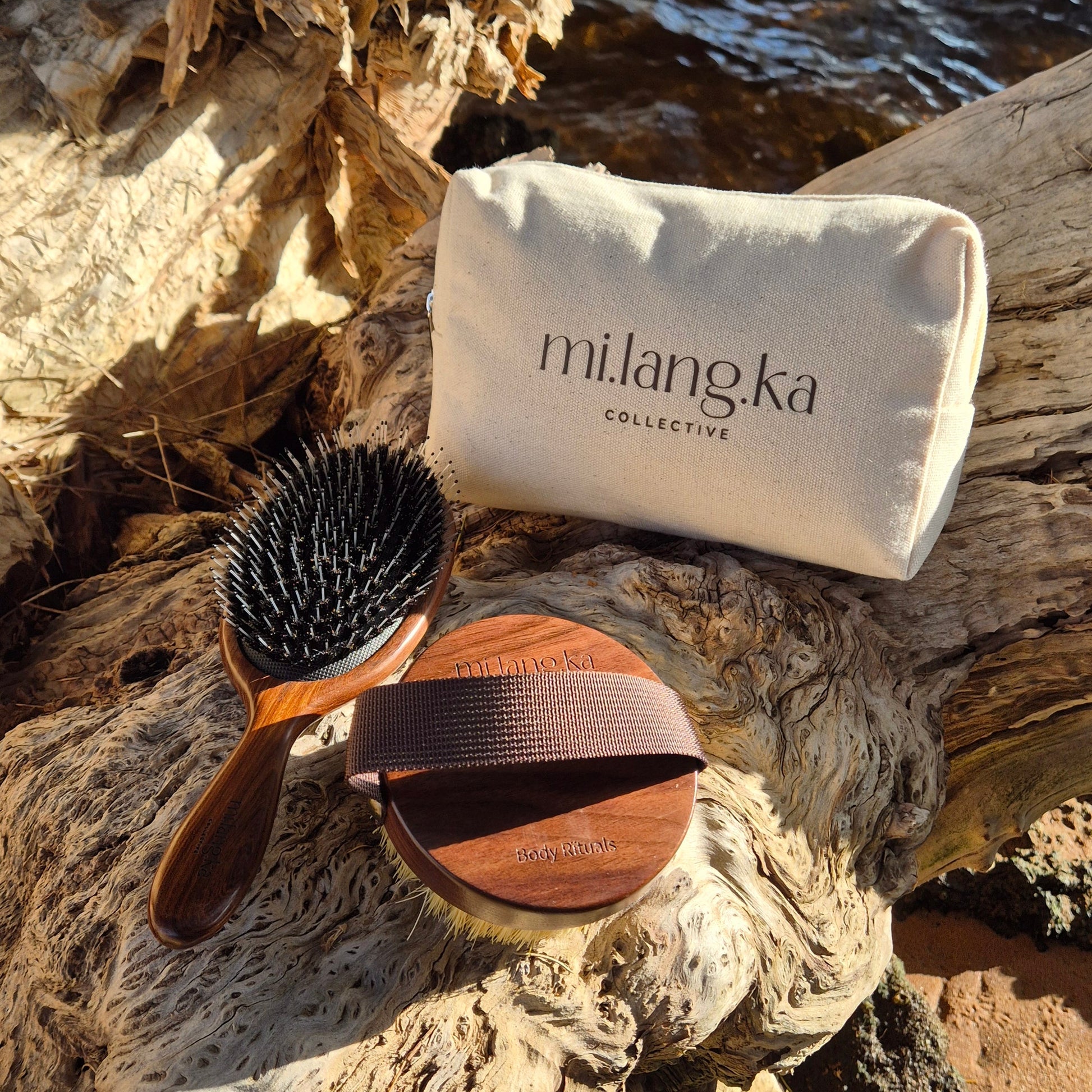 Two brushes and a pouch on a rocky surface with water in the background