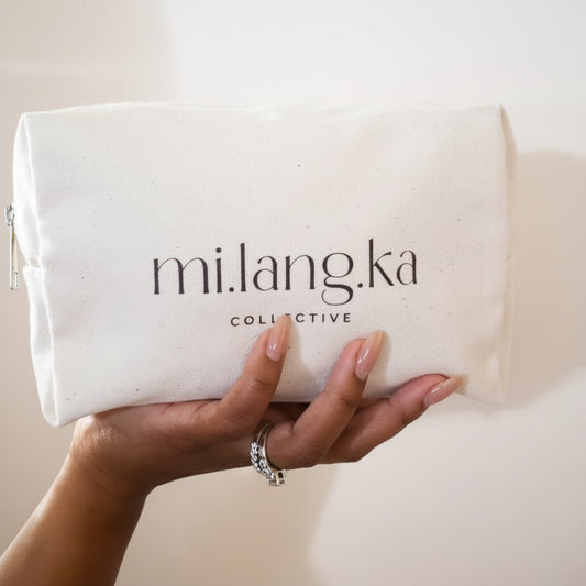 Hand holding a beige pouch with 'mi.lang.ka collective' branding against a neutral background